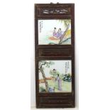 A Chinese hanging screen formed of two famille rose ceramic panels in wooden frame,