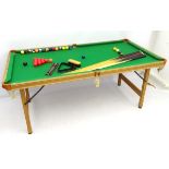 A portable cue-sports table, with green baize top, together with six cues, a boxed set of snooker,