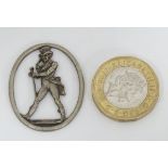 A white metal oval with figural image to centre depicting Johnnie Walker style figure.