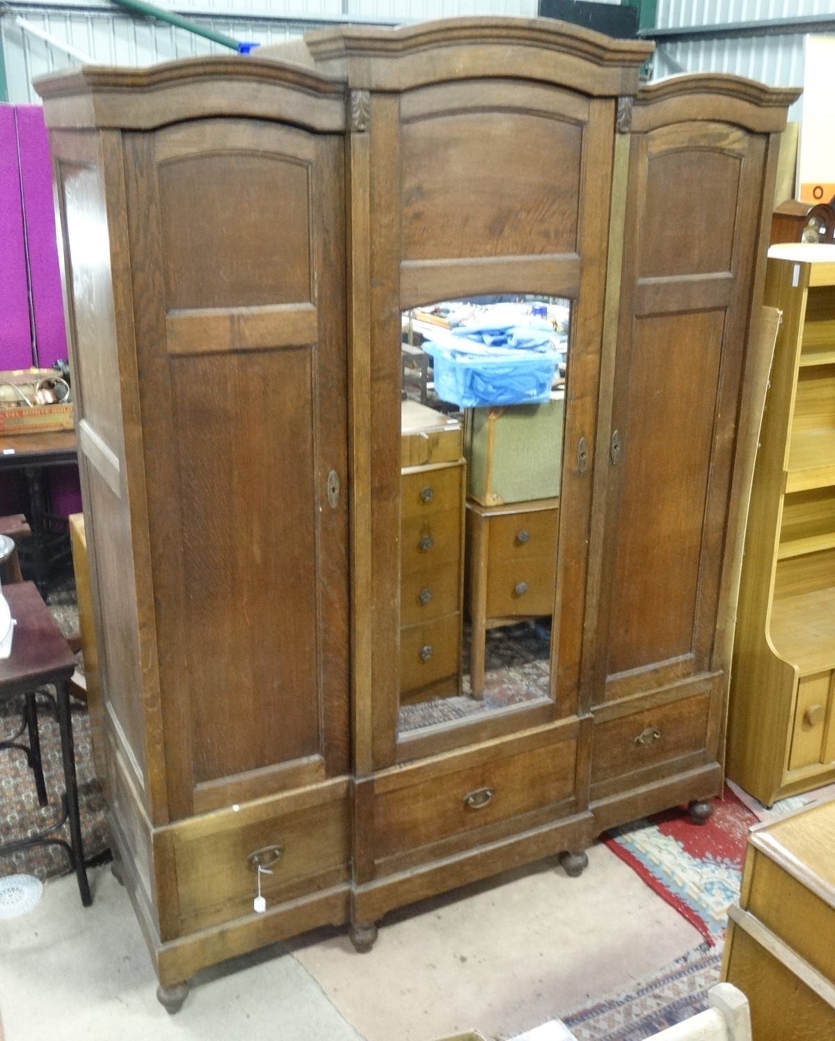 A late 19th / early 20th C oak breakfront triple armoire/ bibliotech with a mirror central door and