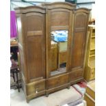 A late 19th / early 20th C oak breakfront triple armoire/ bibliotech with a mirror central door and