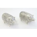 A pair of white metal novelty pepperettes formed as pigs.