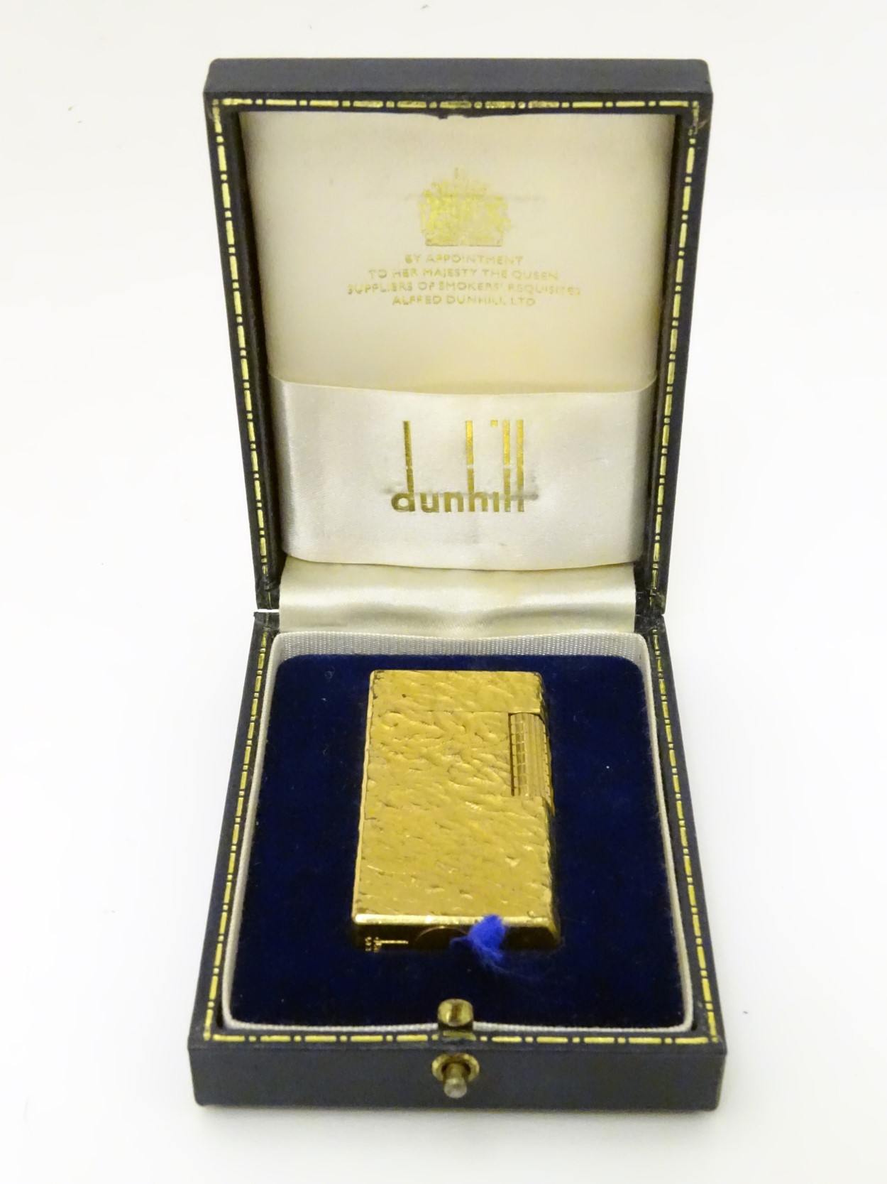 Dunhill: A cased, collectable gold-plated lighter with textured finish.