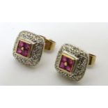 A Pair of silver gilt earrings set with red stones bordered by chip set diamonds