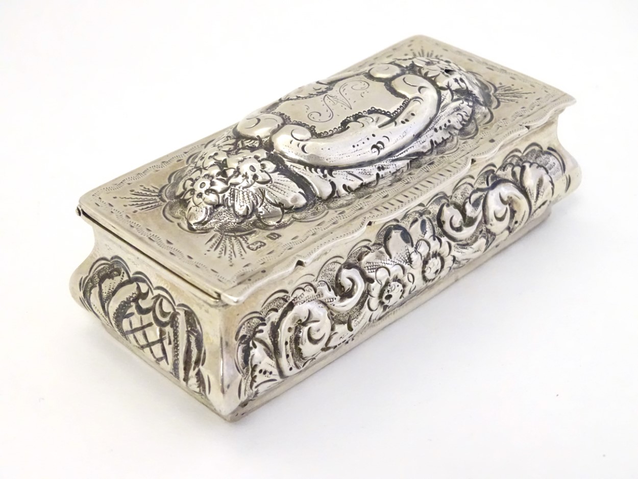 A silver dressing table box with hinge lid and embossed decoration.