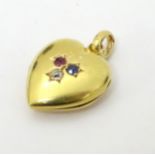 A 15ct and yellow metal locket of heart shape set with a diamond, sapphire and ruby .