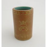 A Chinese brush pot of cylindrical form in burnt orange with gilt coloured highlights,