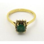 An 18ct gold ring set with central emerald bordered by diamonds in a squared setting.
