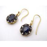 A pair of yellow metal drop earrings set with blue and white stones.