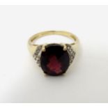 A 9ct gold ring set with facet cut red stone flanked by white stones CONDITION: