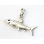 A 14k white gold pendant formed as a shark with blue stone eyes.