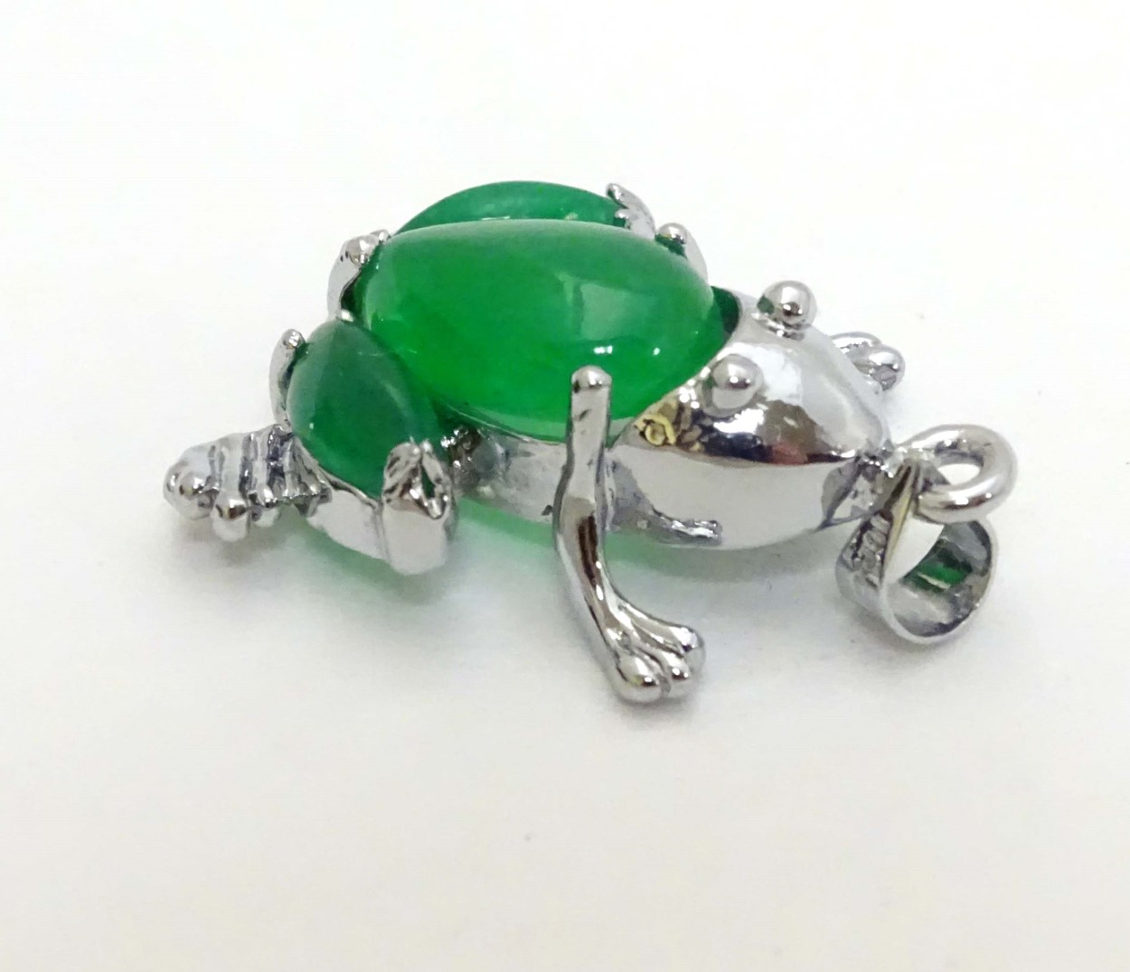 A white metal pendant formed as a frog set with green jade like cabochon 1" long