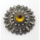 A silver brooch with filigree style decoration set with amber stone to centre 1 ½” wide