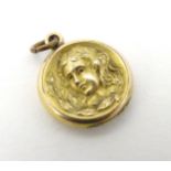 A gilt metal pendant locket with decoration to one side depicting the head of a young girl ¾” wide