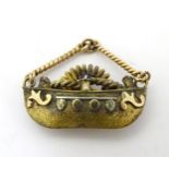 A gilt metal pendant / charm formed as a boat set with red and blue stones.
