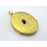 A Continental gold locket of oval form with engraved decoration to front and set with central blue