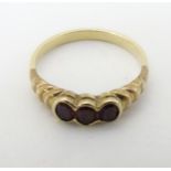 A yellow metal ring set with three garnets CONDITION: Please Note - we do not make