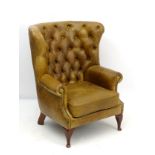 A late 20thC / early 21stC leather button back wing armchair with barrel back,