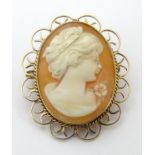 A shell carved classical cameo depicting the head of a woman with flower, within a 9ct gold mount.