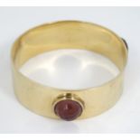 A gilt metal bangle by Lucas Jack London set with facet resin amethyst coloured cabochon decoration