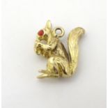 A 9ct gold pendant / charm formed as a squirrel eating a nut, with red stone eyes.