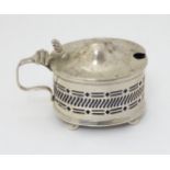 A silver mustard pot with blue glass liner. Hallmarked Birmingham 1932 maker Adie Bros Ltd.