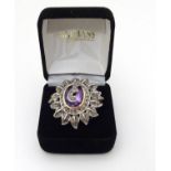 An 18ct gold ring set with large central amethyst adorned and bordered by a profusion of diamonds.