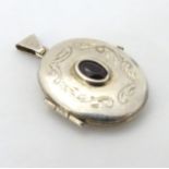 A white metal oval locket pendant set with central garnet.