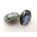 A single silver cufflink having guilloche enamel decoration with silhouette detail in the