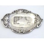 A silver pin dish with thistle decoration to border and interior scene to centre.