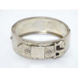 A Victorian silver bracelet of bangle form with buckle detail and engraved decoration.
