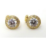A pair of stud earrings set with central large white stones bordered by small white stones marked