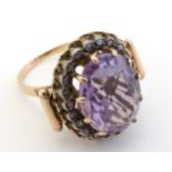 A gold ring set with large central amethyst bordered by diamonds.