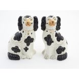 Two Victorian Staffordshire seated spaniels with black patch decoration and gilt lock and chain