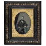 *Half-plate ambrotype of a gentleman seated at a table, early 1860s, tinted, highly ornate chased