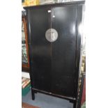 A CONTEMPORARY ORIENTAL WARDROBE in black lacquer, with central circular brass handle with lock, 73"