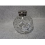 AN EDWARDIAN SILVER MOUNTED CUT-GLASS SCENT BOTTLE of globe form, the screw top engraved with crest,