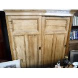 AN EDWARDIAN PINE DOUBLE WARDROBE with two sliding panelled doors, 75" high x 66" wide