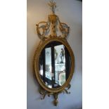 A GILTWOOD OVAL WALL MIRROR of Adam design with central urn decorated with swags, 50" high x 21"