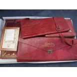 A RED LEATHER STATIONERY FOLDER with contents and other similar red leather bags and related