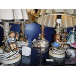 FIVE GOEBEL PORCELAIN TABLE LAMPS, modelled with children sitting beside tree stumps, with