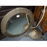 A 1920S CIRCULAR WALL MIRROR in an anodised brass frame and a similar standard lamp (2)