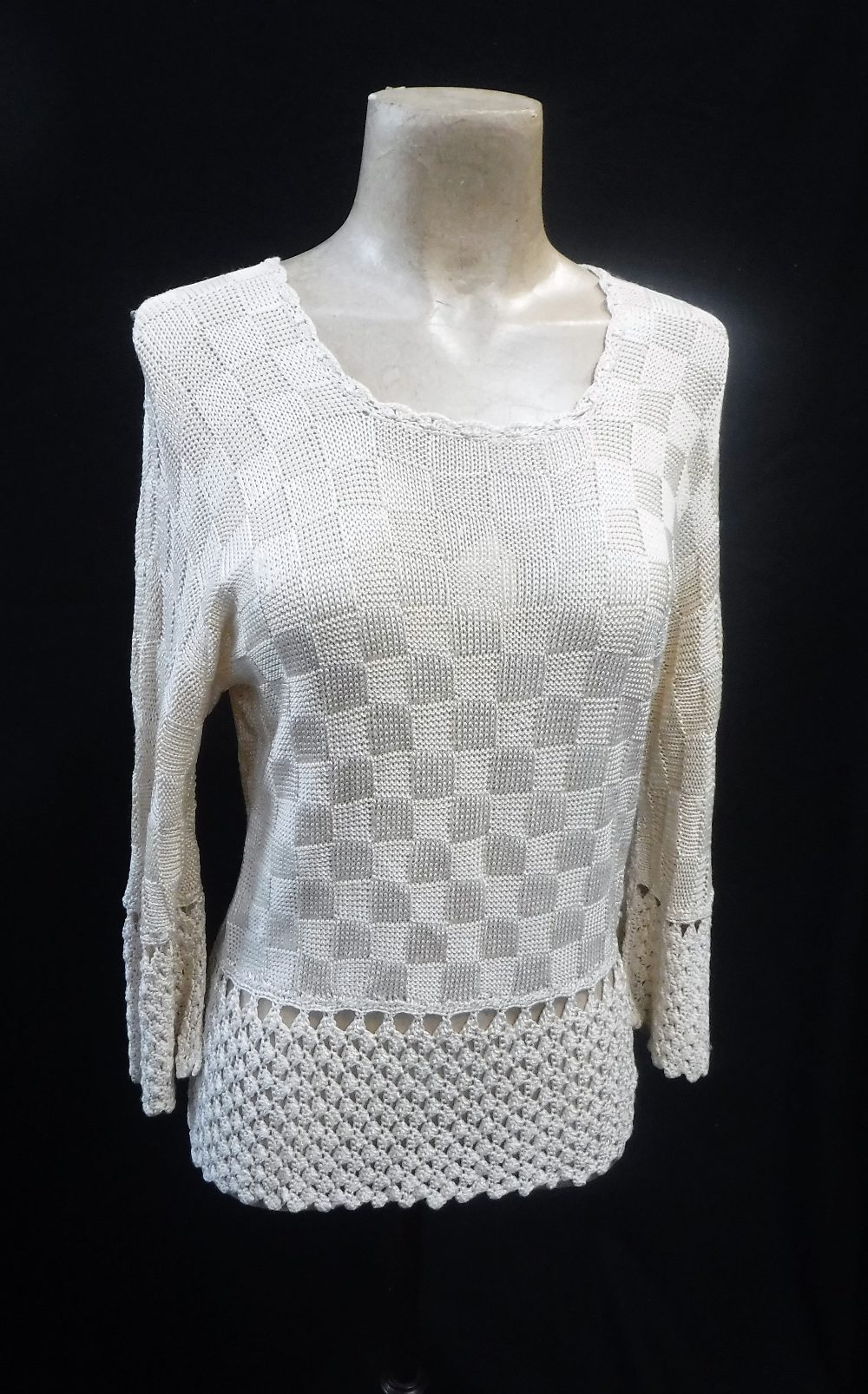 A CREAM 'BAT-WING' KNITTED JUMPER, the waistline, sleeves and neckline with crocheted detail