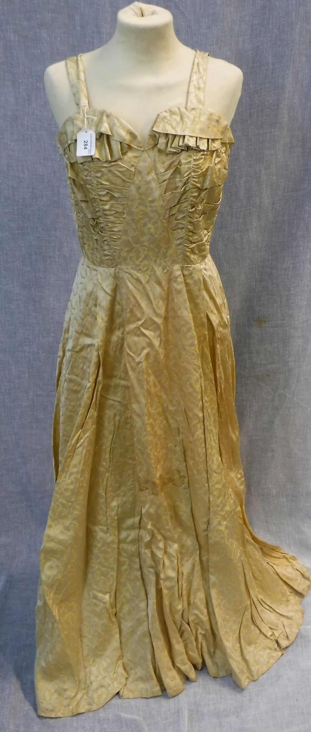 A FULL LENGTH YELLOW BROCADE EVENING DRESS, the rouched fitted bodice falling into a full skirt,