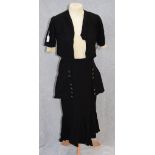 A BLACK SKIRT AND MATCHING JACKET, the skirt with overlaid black panel, decorated with cream and