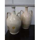 A PAIR OF CREAM GLAZED TWIN HANDLED PORTUGUESE POTTERY VASES with narrow necks and bellied bodies,