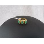AN EMERALD THREE STONE DRESS RING, the three oval-cut cabochon emeralds set in a yellow gold twisted