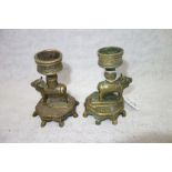 A PAIR OF EASTERN BRASS CANDLESTICKS supported by a pair of beasts, 11 cm high