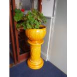 A BURMANTOFTS FAIENCE GLAZED JARDINIERE AND STAND in bright yellow, with floral embossed decoration,