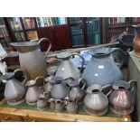 A LARGE COLLECTION OF COPPER SACK MEASURES of graduating size and a large brass jug